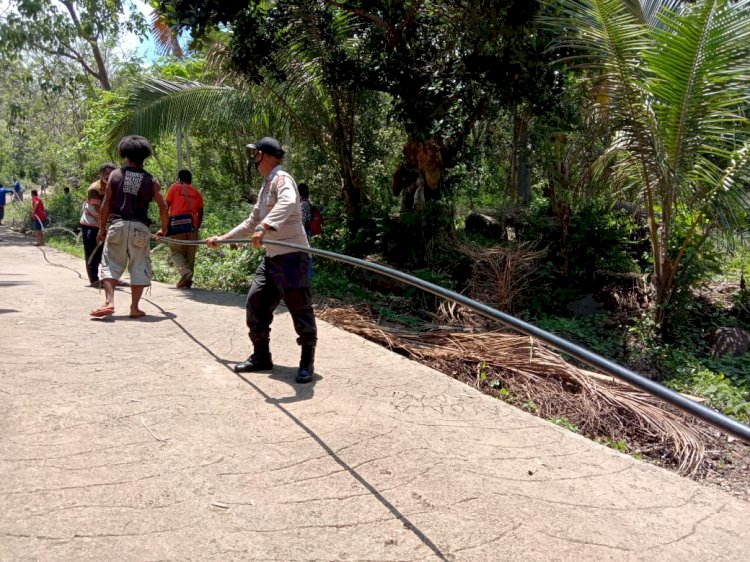 Kanit Binmas Polsek Bola Bersama Warga Gotong Royong Memasang Saluran Air Bersih